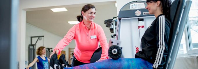 Eine Gruppe macht Krafttraining an Maschinen und auf einem Gymnastikball