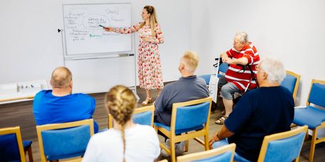 Mitarbeiterinnen erläutern einer Gruppe die Faktoren, die das Gewicht beeinflussen. 