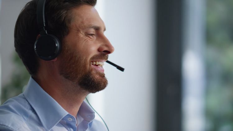 Bärtiger Mann spricht im Callcenter in sein Headphone