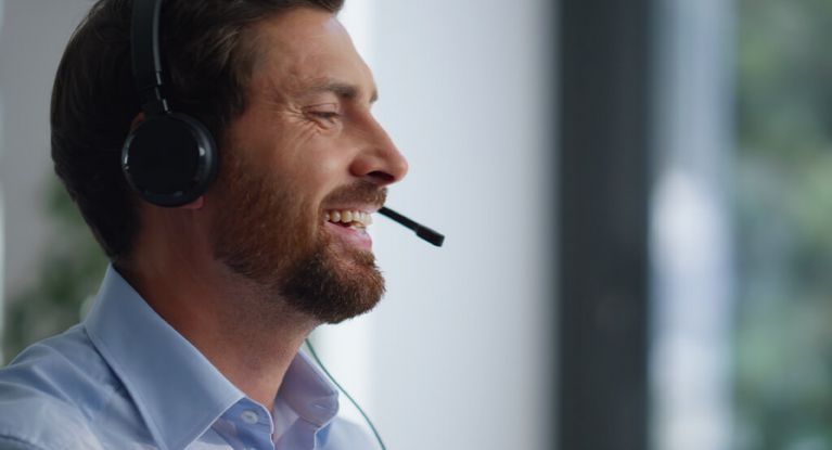 Bärtiger Mann spricht im Callcenter in sein Headphone