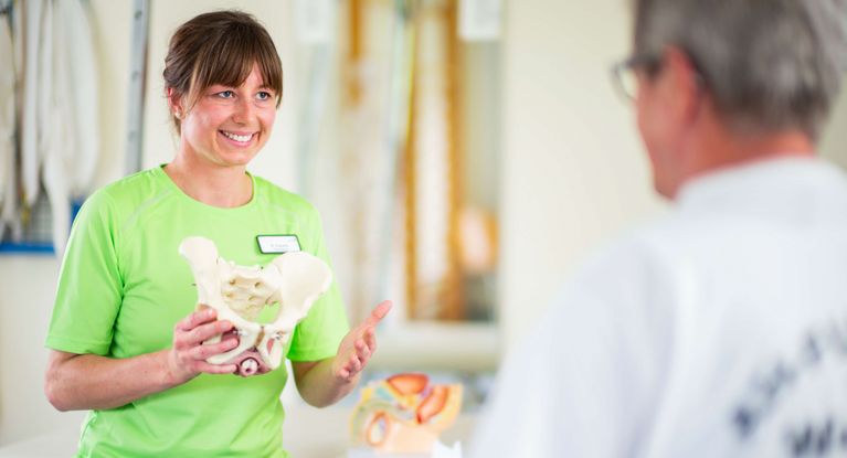 Therapeutin erläutert Funktion der Beckenknochen am Modell