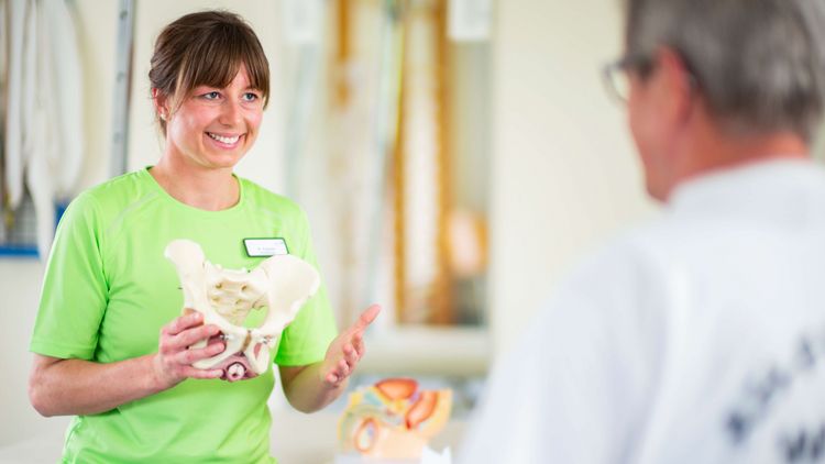 Therapeutin erläutert Funktion der Beckenknochen am Modell