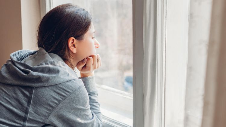 Traurige Frau schaut aus dem Fenster