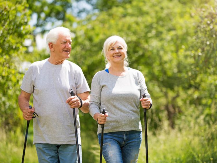 ein älteres Paar spaziert mit Nordic-Walking-Sticks im Wald