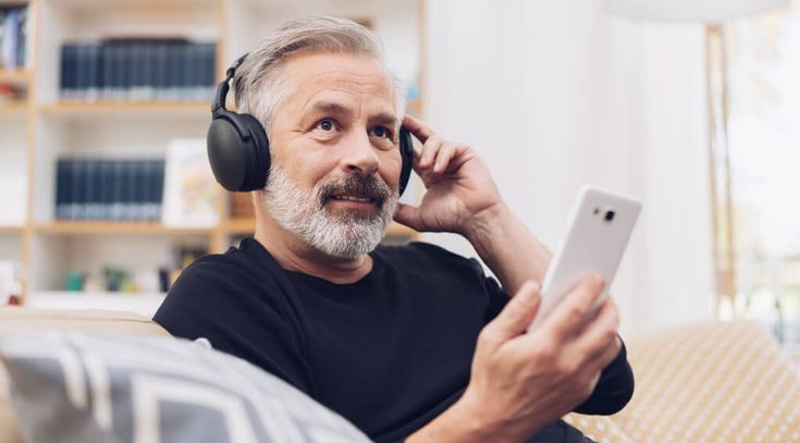 Mittealter Mann mit Kopfhörer hört Musik auf dem Smartphone