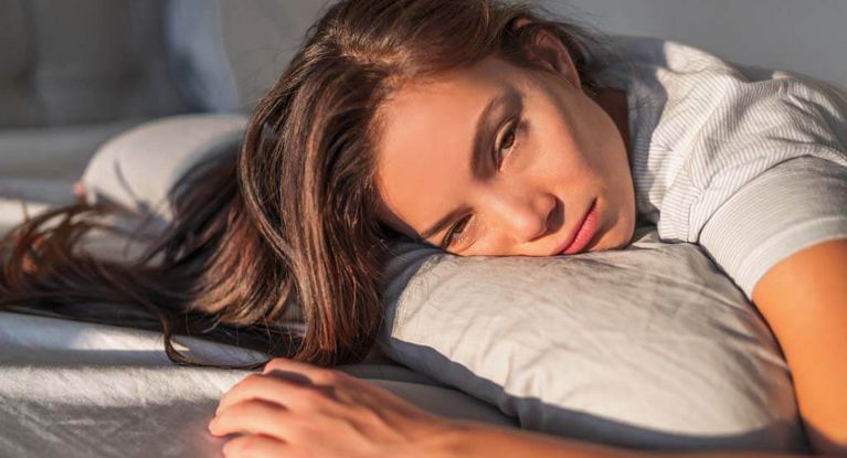 Schlaflose junge Frau liegt auf einem Kissen und kann nicht schlafen