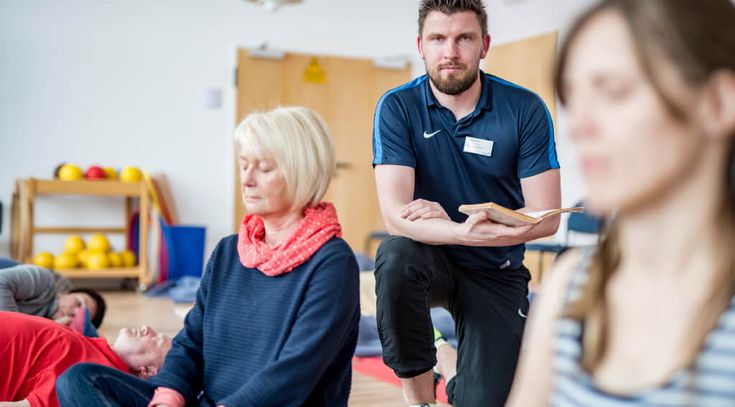 Ein Trainer betreut eine Gruppe bei den Entspannungsübungen 