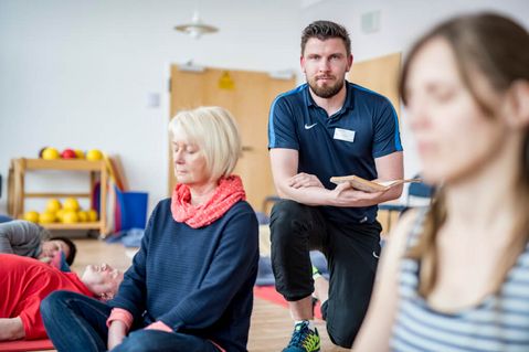 Ein Trainer betreut eine Gruppe bei den Entspannungsübungen 
