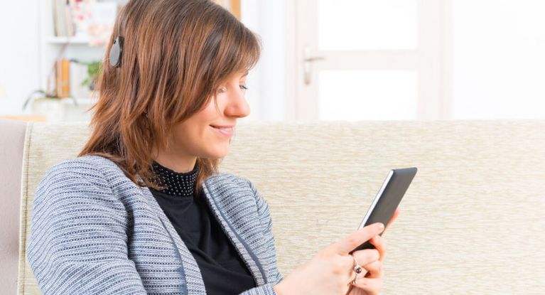 Frau mit Cochlea Implantat hört Musik am Smartphone