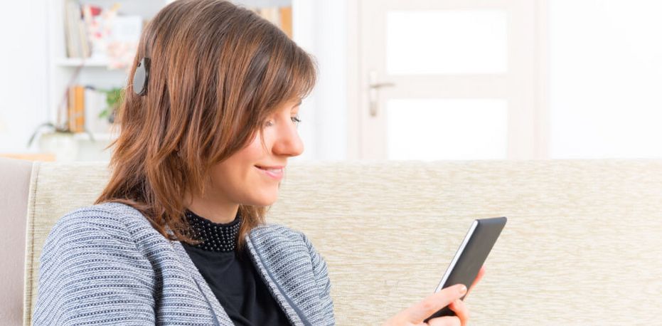 Frau mit Cochlea Implantat hört Musik am Smartphone