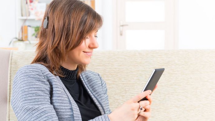 Frau mit Cochlea Implantat hört Musik am Smartphone