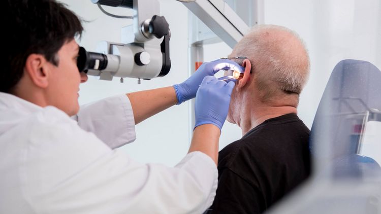 Patient wird mit einer Lampe im Ohr untersucht