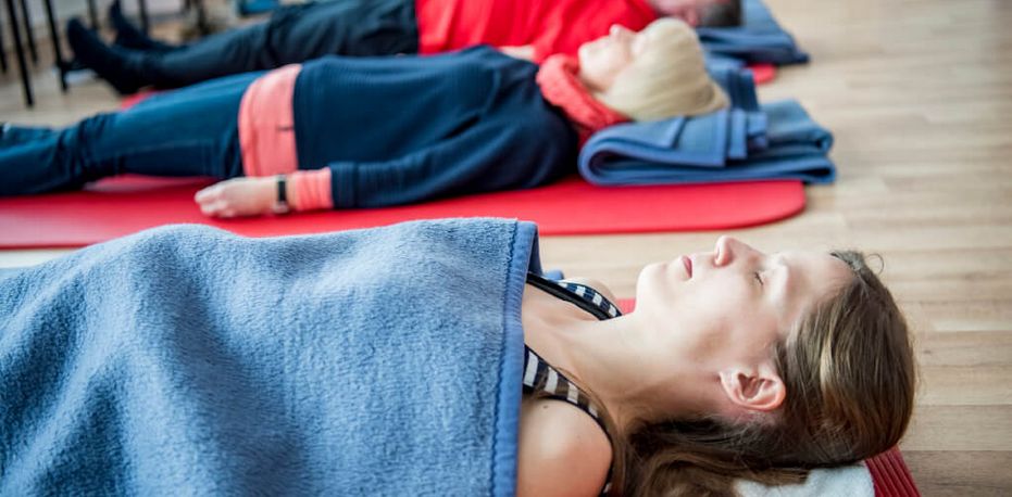 Eine Gruppe liegt auf dem Boden und macht Entspannungsübungen