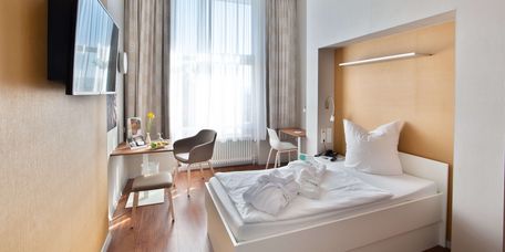 Ein Patientenzimmer mit großem Fenster und einem Bademantel auf dem Bett