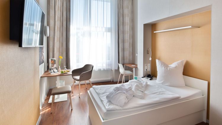 Ein Patientenzimmer mit großem Fenster und einem Bademantel auf dem Bett