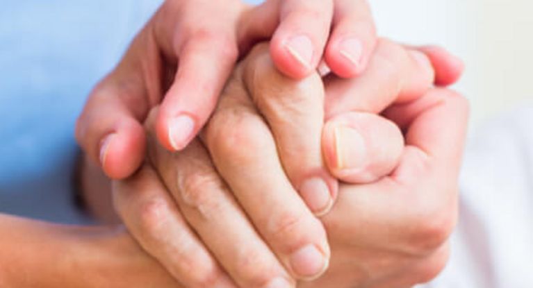 Pflegerin hält die Hand eines älteren Patienten