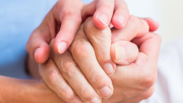 Pflegerin hält die Hand eines älteren Patienten