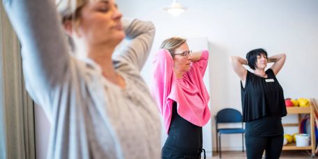 Eine Gruppe macht Entspannungsübungen und dehnt sich dabei