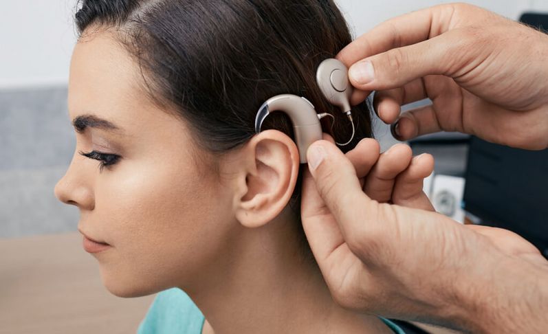 Fachkraft stellt Cochlea Implantat am Kopf einer Patientin ein