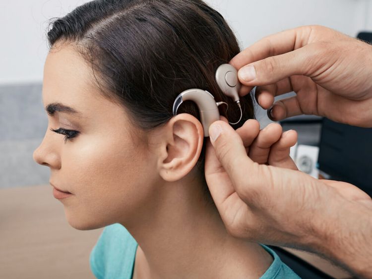 Fachkraft stellt Cochlea Implantat am Kopf einer Patientin ein