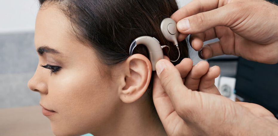 Fachkraft stellt Cochlea Implantat am Kopf einer Patientin ein