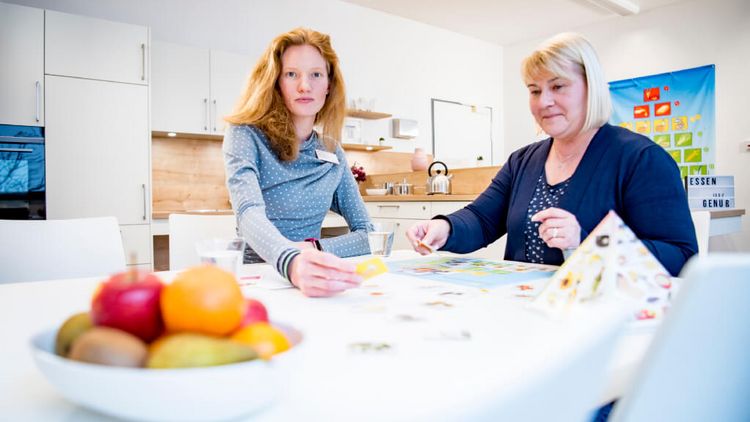 Eine Ernährungsberaterin klärt einer Patientin in der Küche über gesunde Lebensmittel auf