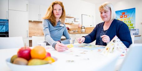 Eine Ernährungsberaterin klärt einer Patientin in der Küche über gesunde Lebensmittel auf