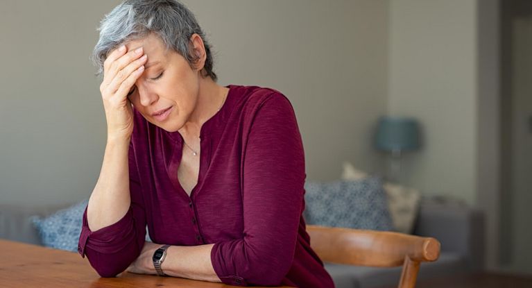 Ältere Frau stützt erschöpft ihren Kopf auf die Hand