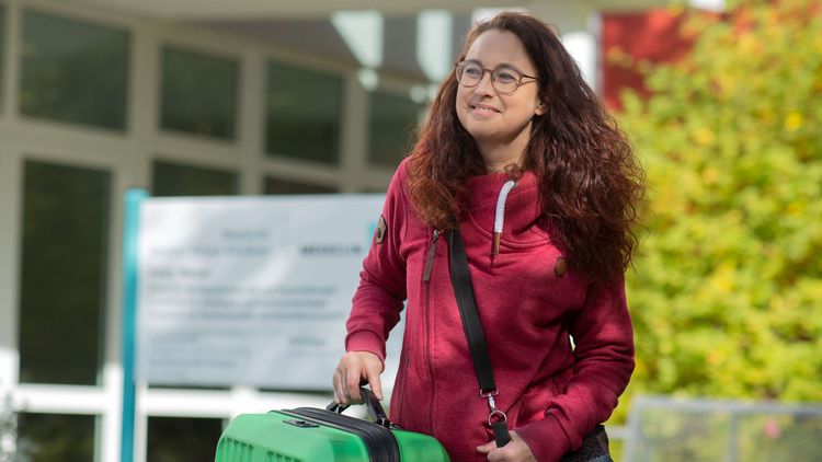 Patientin mit Koffer steht vor den Deister Weser Kliniken