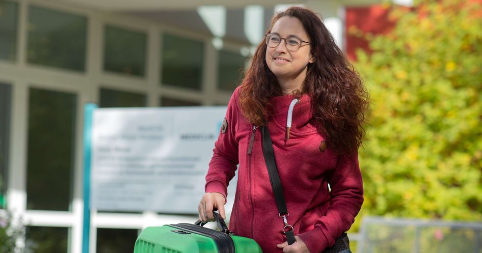 Patientin mit Koffer steht vor den Deister Weser Kliniken