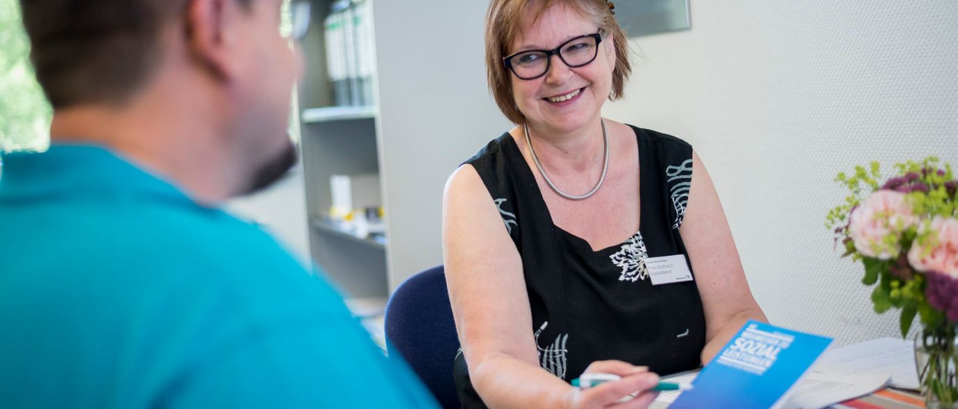 Eine Mitarbeiterin des Sozialdienstes berät einen Patienten vor der Entlassung aus der Klinik